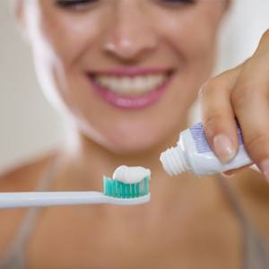 A woman applying toothpaste to a toothbrush