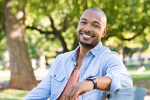 attractive, smiling man sitting at the park