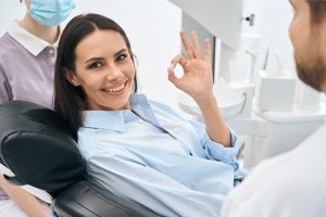 woman doing an okay sign and having a good dental checkup and cleaning appointment 