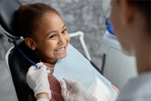 little girl smiling in the dental chair before a dental exam and cleaning appointment 