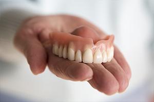 Hand holding full dentures