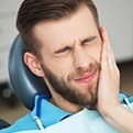 Man in pain holding cheek before emergency dentistry