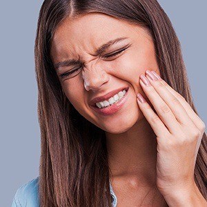 Young woman holding cheek in pain before wisdom tooth extraction