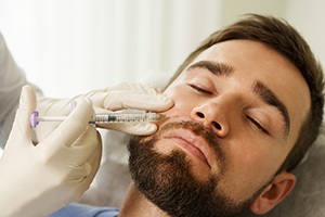 bearded man closing his eyes and getting dermal fillers