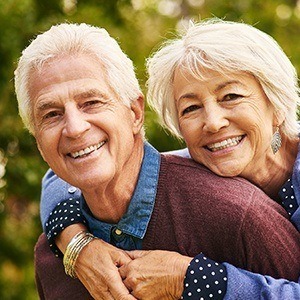 Smiling senior couple outdoors after restorative dentistry