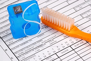 toothbrush and floss with a form for dental insurance in Crete