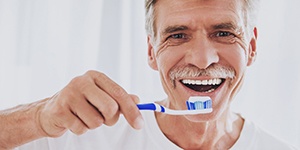 man brushing his teeth and dental implants in Lincoln