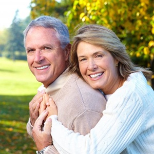 Man and woman with dental implant retained dentures smiling outdoors