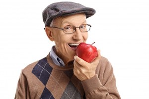 Man with dental implant retained dentures eating an apple