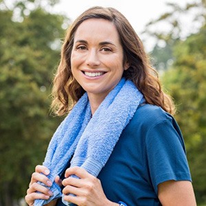 A woman smiling outside with a towel around her neck after Invisalign treatment