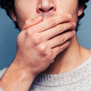 Man with cracked teeth covering mouth