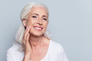 Smiling woman showing off her beautiful dental implants in Lincoln