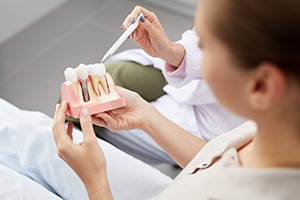 Patient holding a model and learning about dental implants in Lincoln