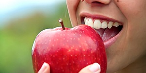 Closeup of patient with dental implants in Lincoln eating an apple