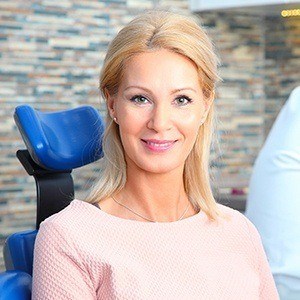Smiling woman in dental chair after professional teeth cleaning visit