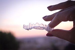 Hand holding a clear Invisalign tray