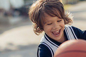 Young boy playing basketball after children's dentistry