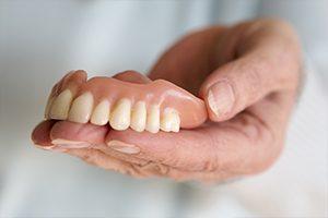 Hand holding a full denture