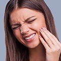 Woman holding cheek in pain before emergency dentistry