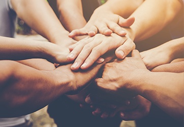 Group of people placing hands in center of a circle