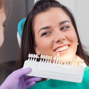 A dentist comparing porcelain veneer shades to a patient’s smile
