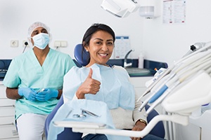 woman giving thumbs up in a dental chair (for the Benefits of Root Canal Therapy section)
