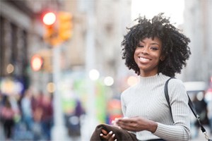 Woman in a white sweater walking down street smiling