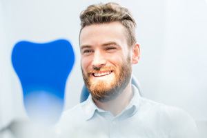 Man looking at smile in mirror after teeth whitening in Lincoln, NE