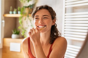 Woman smiling and brushing her teeth in bathroom