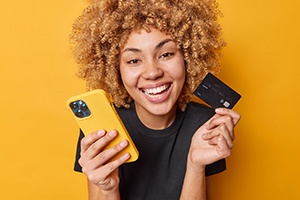woman with white teeth, a phone, and a credit card