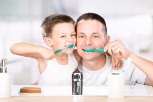 father and son brushing teeth