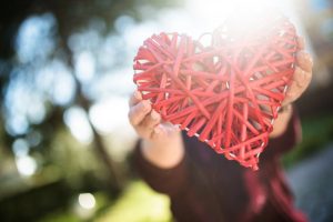 A person holding a threaded heart.