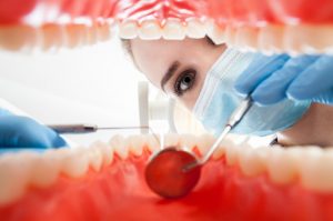 A woman performing an oral cancer screening.