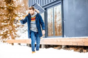 man holding a shovel and dealing with winter mouth issues