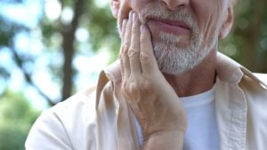 man covering his mouth not knowing if he has gingivitis or oral cancer