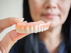 woman holding a denture in front of her