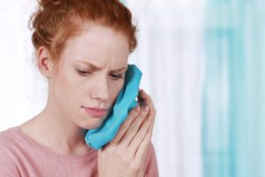 young woman holding her jaw in pain