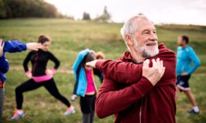 older man stretching with a group getting ready to exercise