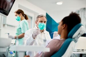 dentist and patient talking with an assistant in the background