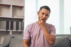 man holding his face with sore gums