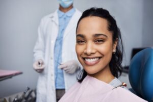 smiling woman in the dentist chair with her dentist in the background