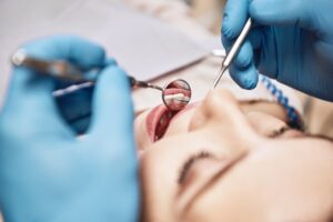 a patient being examined with dental tools looking inside her mouth
