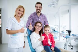 family and dentist smiling with thumbs up