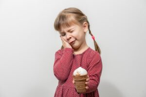 a little girl holding an ice cream cone and her face
