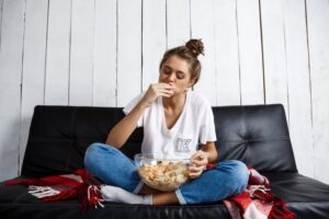 young woman casually eating chips on the couch