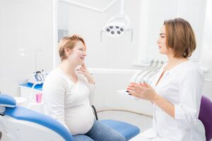 pregnant patient talking to her dentist about dental implants