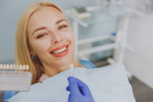 woman smiling with a color guide for veneers next to her face