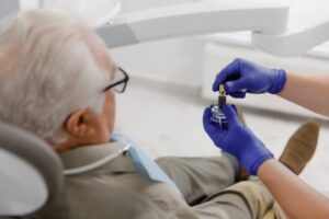 dentist showing an older patient a model of a dental implant