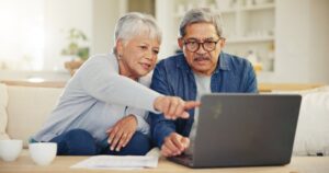 two older adults talking and pointing to a laptop