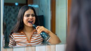 woman using a water flosser in front of a mirror